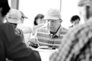 Man eating with other senior citizens